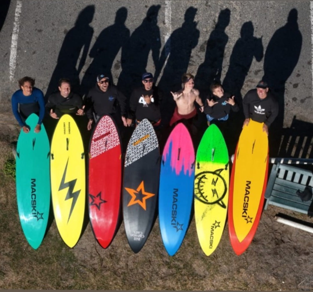 Group of people holding colorful Macski waveskis with various designs.